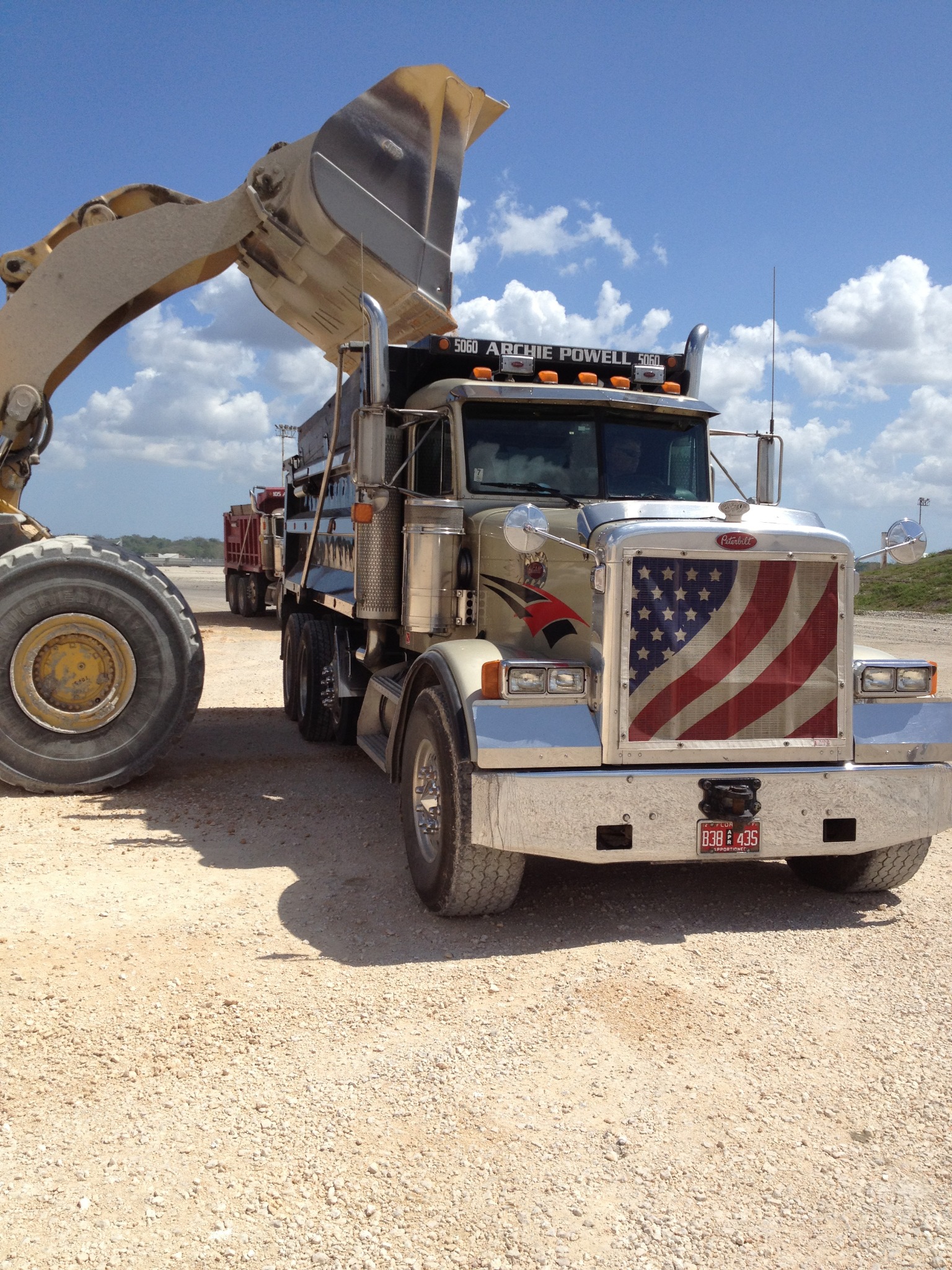 Archie Powell Inc. dump truck being loaded on a job site